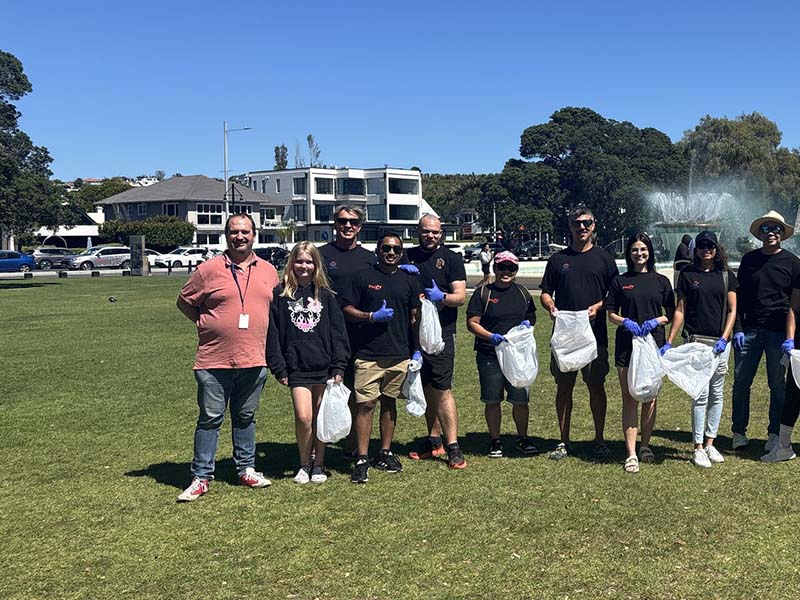 epay New Zealand team members collecting litter along Mission Bay beach during their Day of Caring community clean-up event