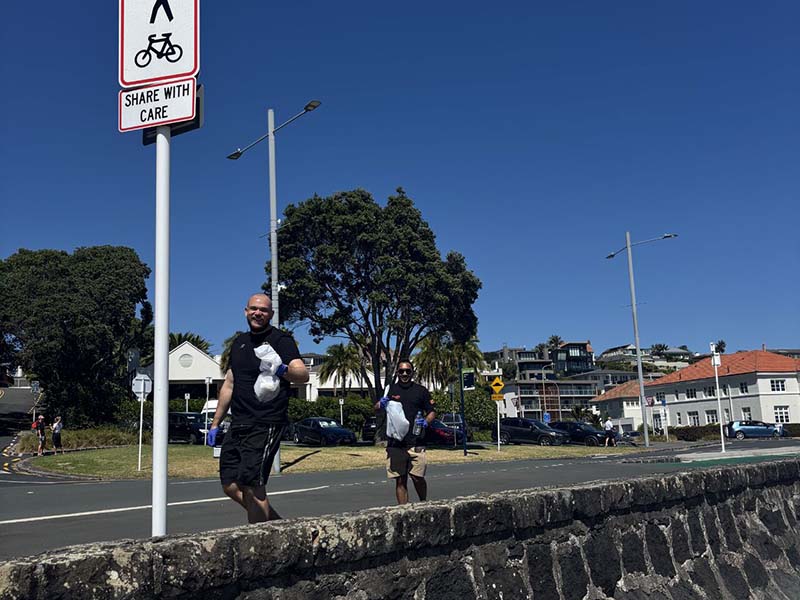 epay New Zealand team members collecting litter along Mission Bay beach during their Day of Caring community clean-up event