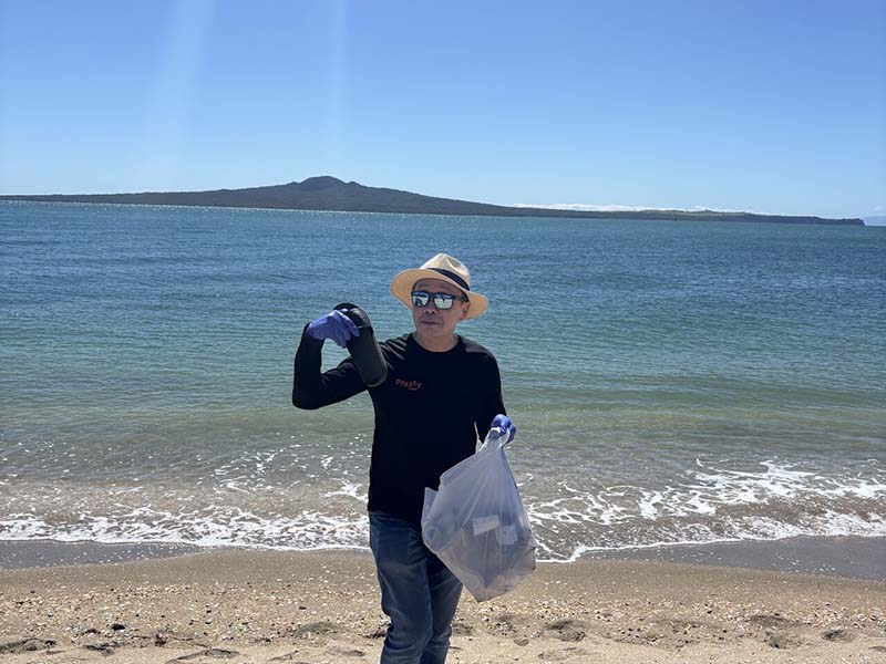 epay New Zealand team members collecting litter along Mission Bay beach during their Day of Caring community clean-up event