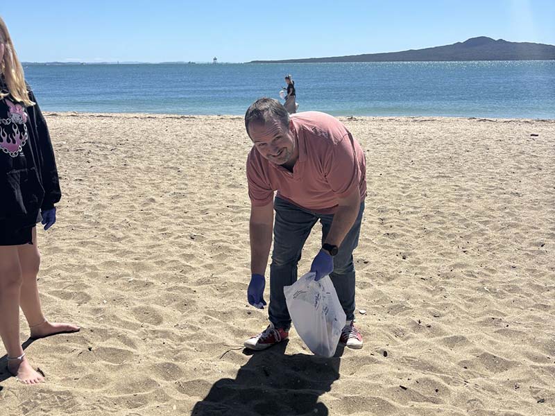 epay New Zealand team members collecting litter along Mission Bay beach during their Day of Caring community clean-up event
